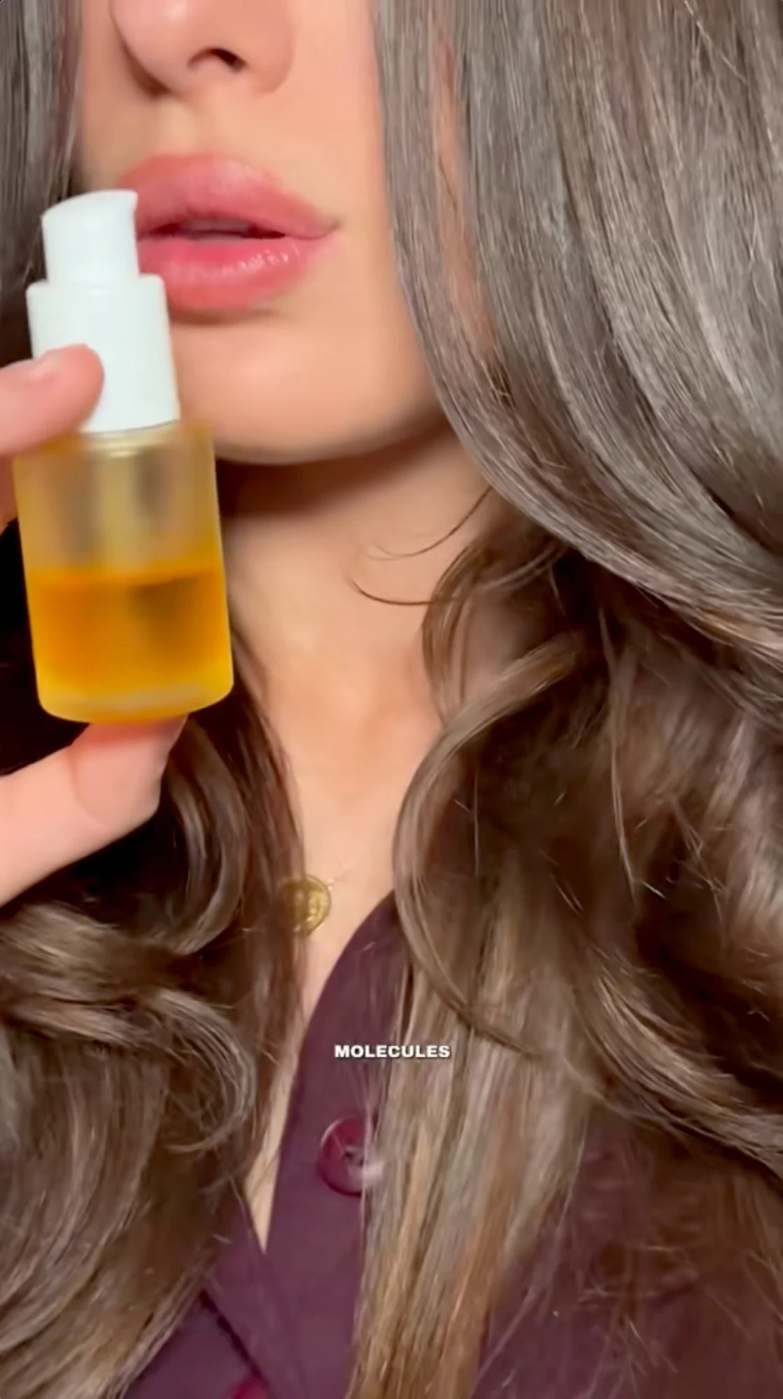 JUVA length maximizing pre-wash hair oil held beside long, glossy waves